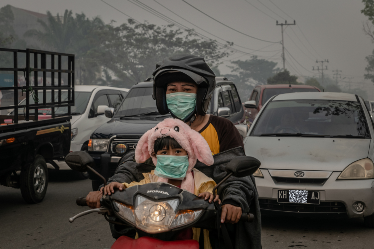 Motorists wear masks as they make their way along a road shrouded in haze from the peat forest fires in Palangkaraya city, Central Kalimantan ©Ulet  Ifansasti/Greenpeace